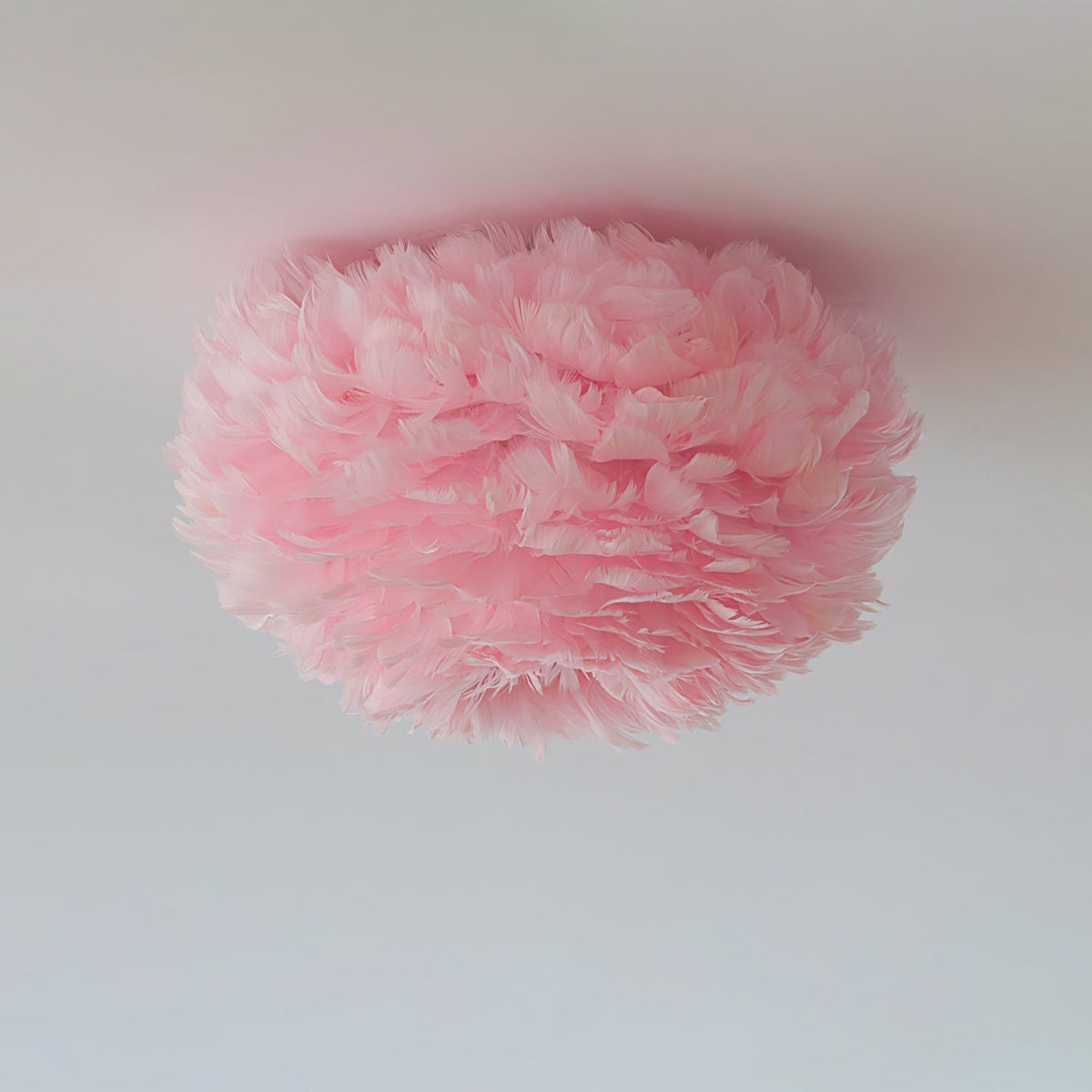 Unlit pink goose-feather ceiling light from Clérachic with soft layered feathers, seen from below on a grey ceiling.