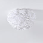 Unlit white goose-feather ceiling light from Clérachic, with fluffy feathers layered into a rounded shade, on a pale grey ceiling.