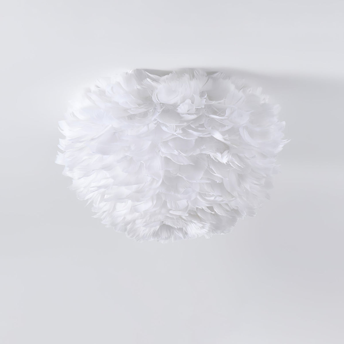 Unlit white goose-feather ceiling light from Clérachic, with fluffy feathers layered into a rounded shade, on a pale grey ceiling.