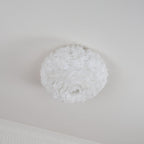 Unlit white feather ceiling light from Clérachic with an open centre underneath, hung flush on a white ceiling by a cornice.