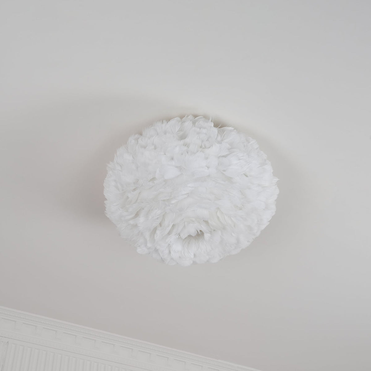 Unlit white feather ceiling light from Clérachic with an open centre underneath, hung flush on a white ceiling by a cornice.