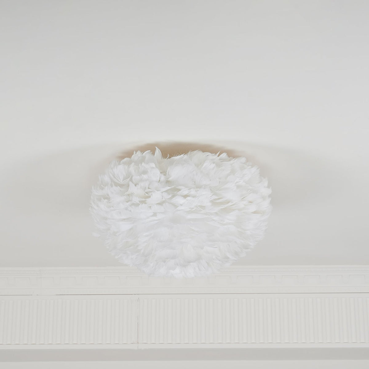 Smaller white feather ceiling light from Clérachic unlit on a white ceiling above a plaster cornice.