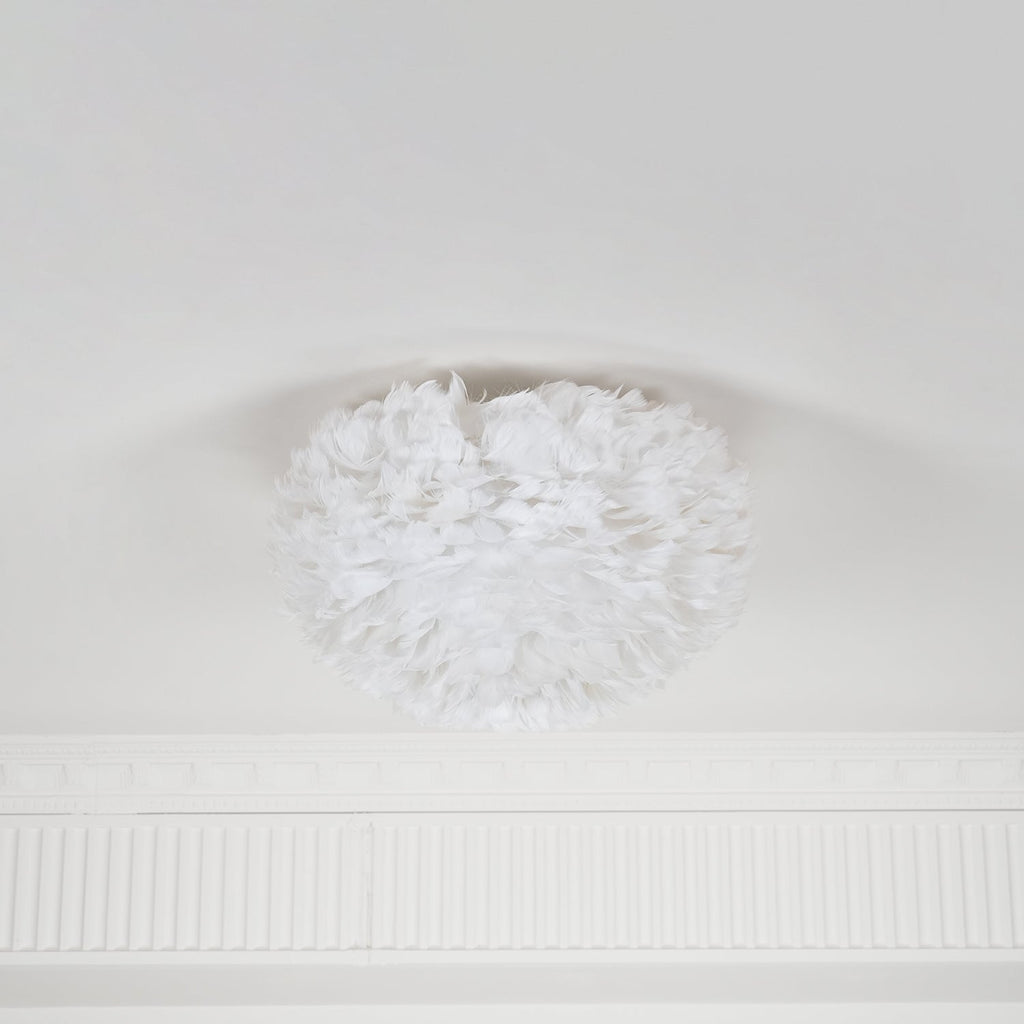 White goose-feather ceiling light from Clérachic, unlit, with feathers curling inward at the top where it meets a white ceiling.