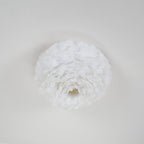Underside of a white feather ceiling light from Clérachic, showing the feathers swirling round a small central opening.