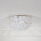 Unlit white feather ceiling light from Clérachic on a white ceiling above a ribbed plaster cornice, seen from the side.