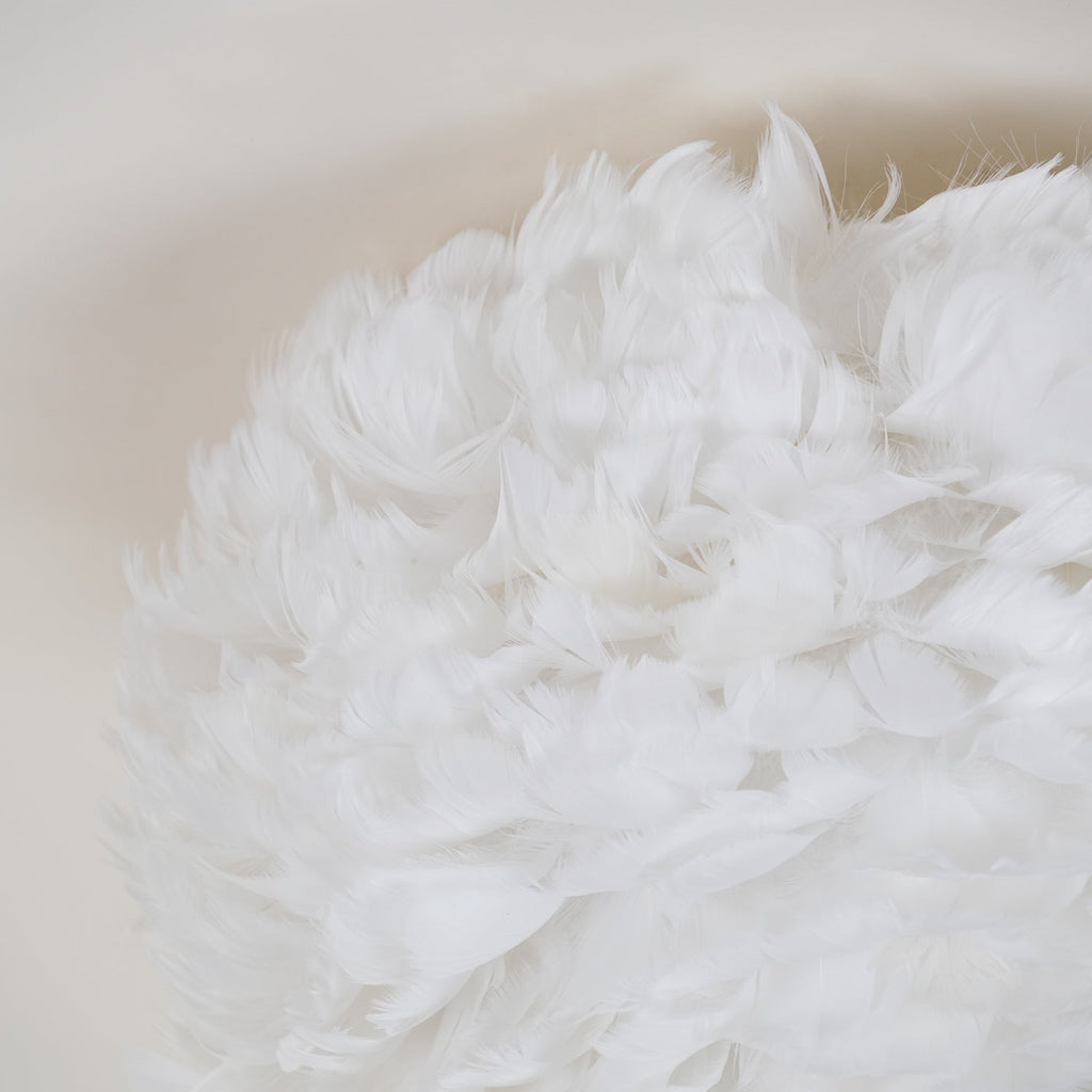 Close view of soft white goose feathers layered on the shade of this Clérachic ceiling light.