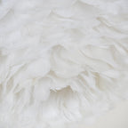 Close view of the underside of this Clérachic feather ceiling light, where long white feathers overlap around the opening.