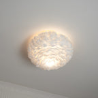 Lit white feather ceiling light from Clérachic with a warm glow on the ceiling and a bright patch under the shade.
