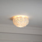 Feather ceiling light from Clérachic lit warm, seen from the side with a cornice and wall panelling beneath it.