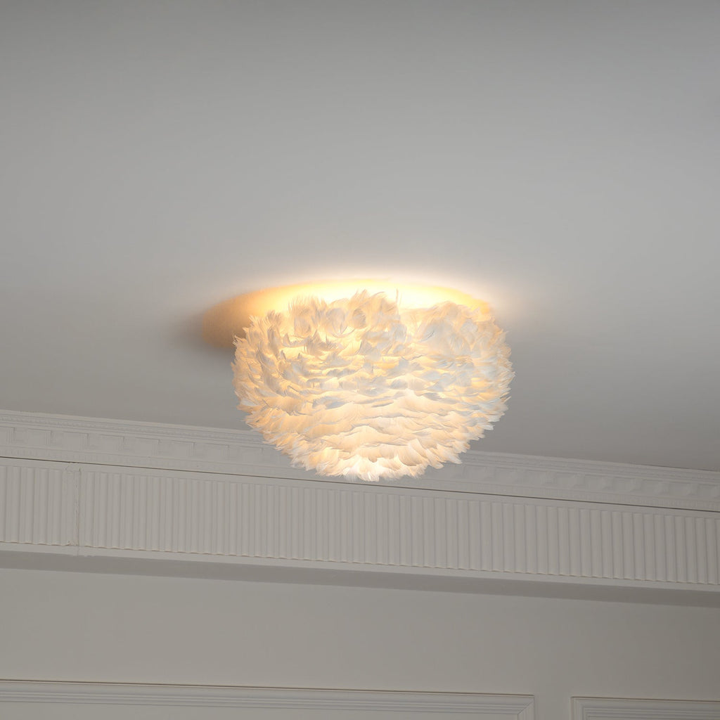 Smaller white feather ceiling light from Clérachic glowing warm on the ceiling above panelling and a cornice.