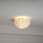 Smaller white feather ceiling light from Clérachic glowing warm on the ceiling above panelling and a cornice.