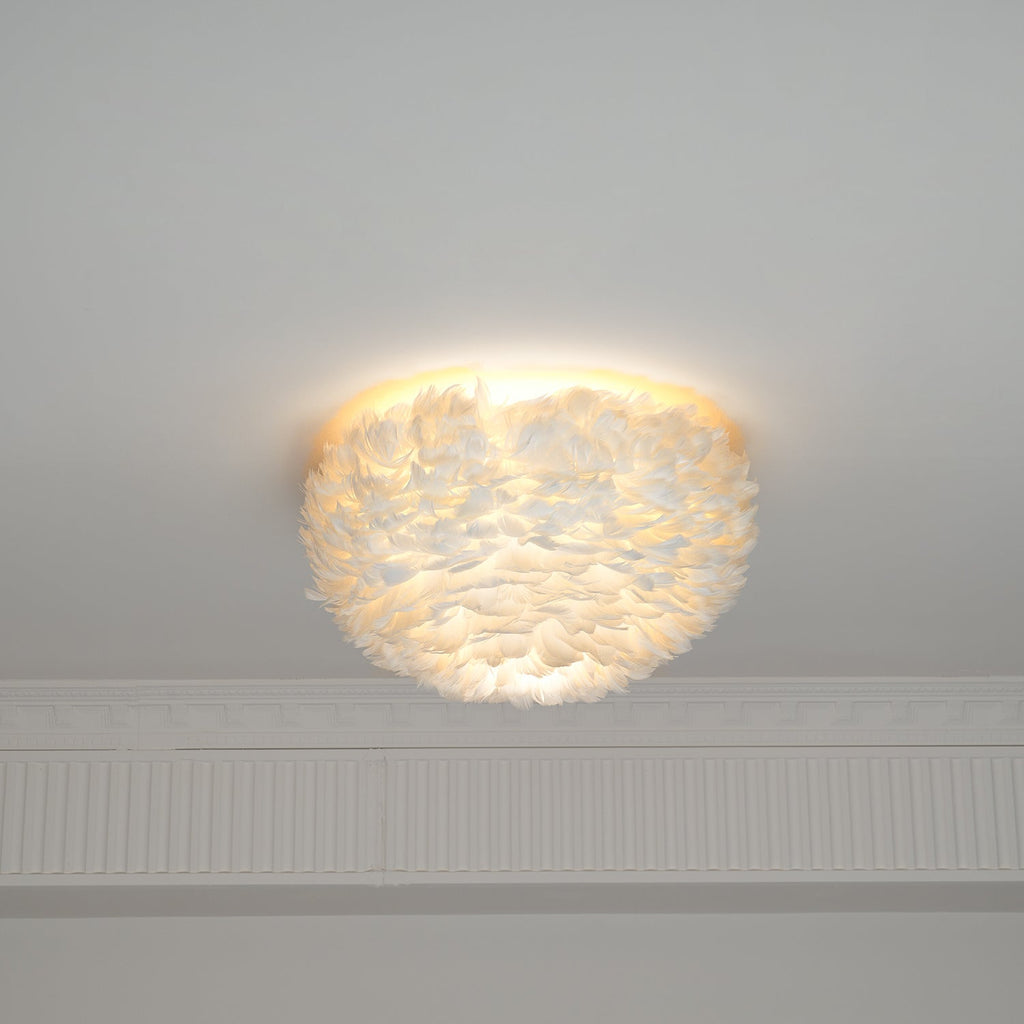 White feather ceiling light from Clérachic lit, with light glowing through the feathers and spilling up over the ceiling.