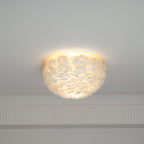 White feather ceiling light from Clérachic lit, with light glowing through the feathers and spilling up over the ceiling.