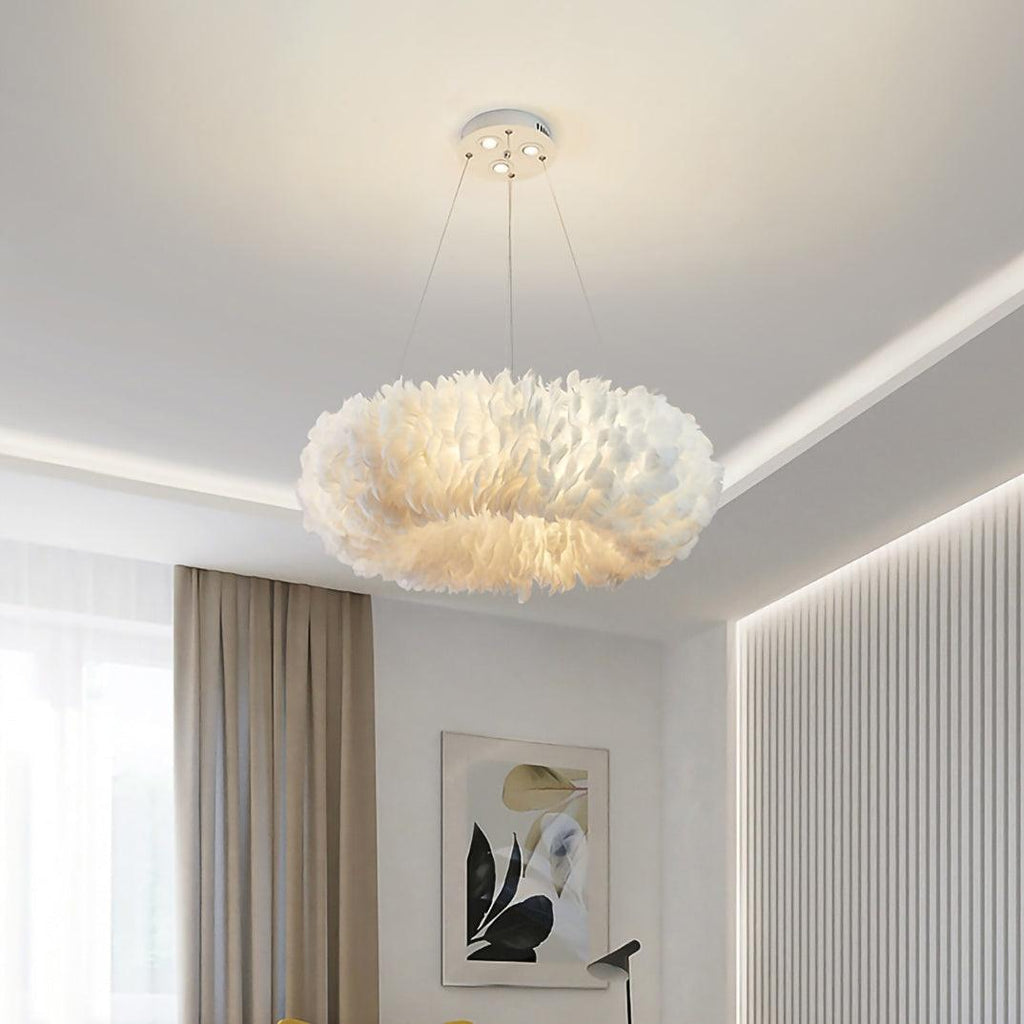 Above a bedroom with a cove-lit ceiling and taupe curtains, this Clérachic pendant shows a lit ring of layered white feathers.