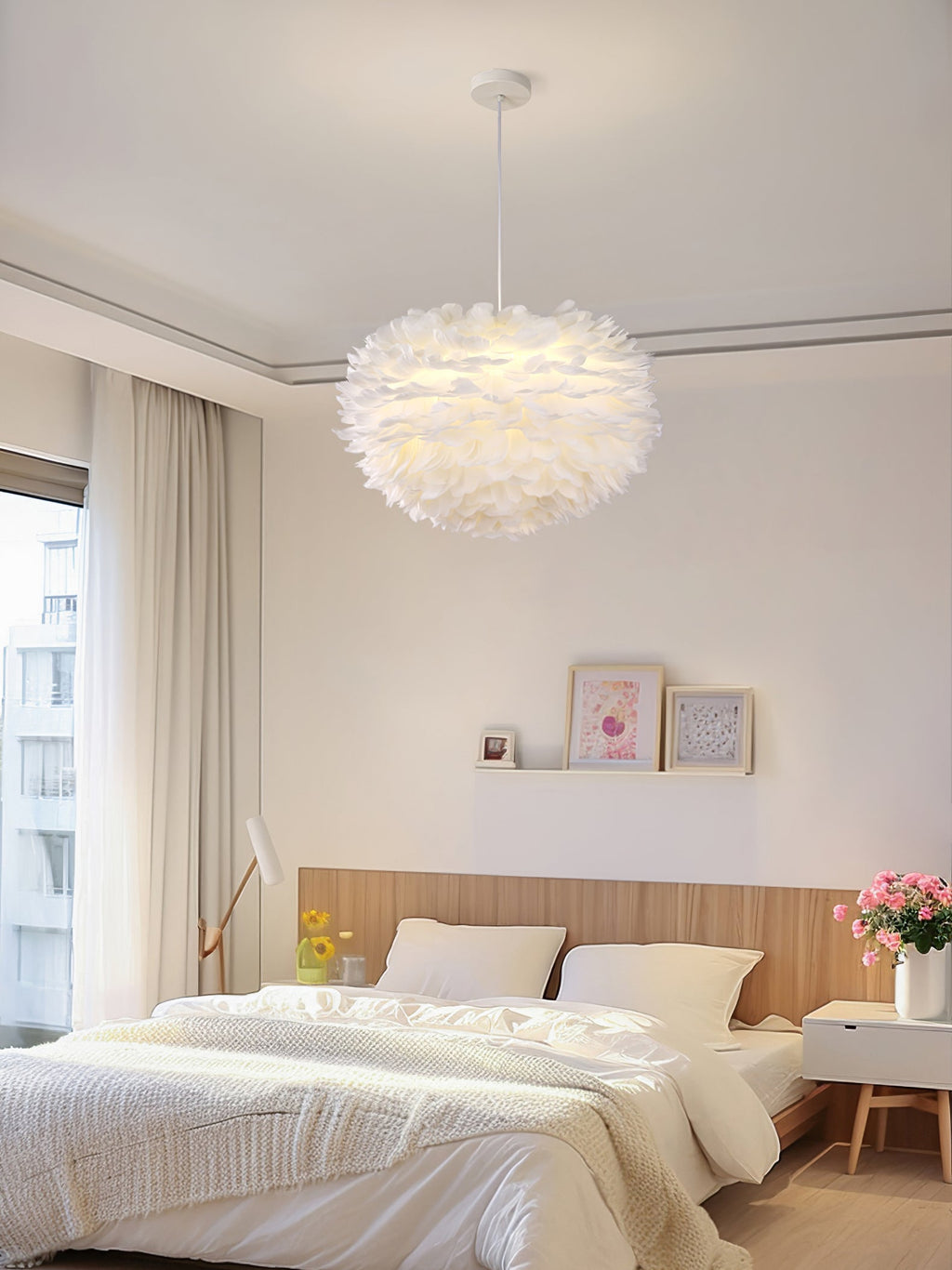 Centred in a pale bedroom with a wooden headboard, this Clérachic feather pendant gives off a soft warm glow.