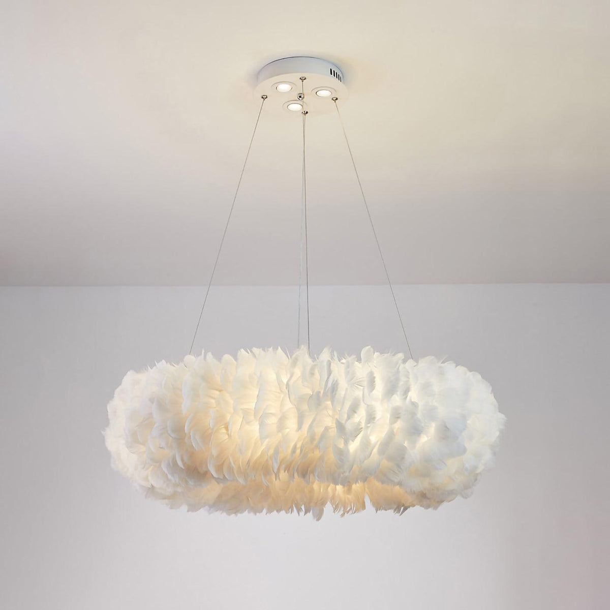 Lit feather ring of a Clérachic pendant, seen from below on its three cables and white canopy with spotlights.