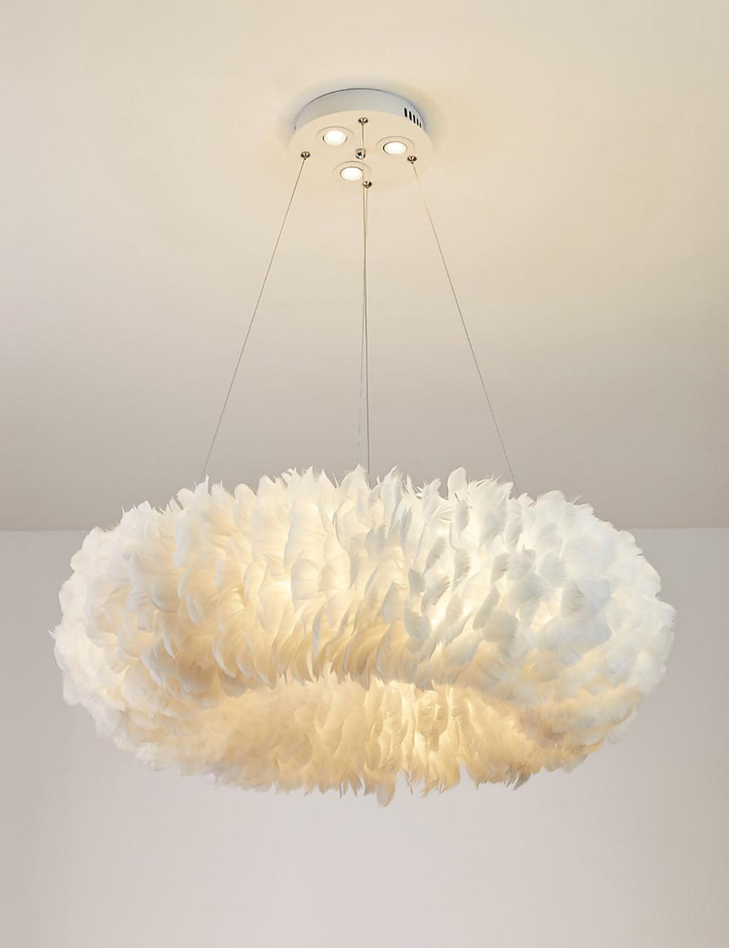 The same Clérachic ring pendant with its glow slightly lower, shown against a pale wall under a white ceiling.