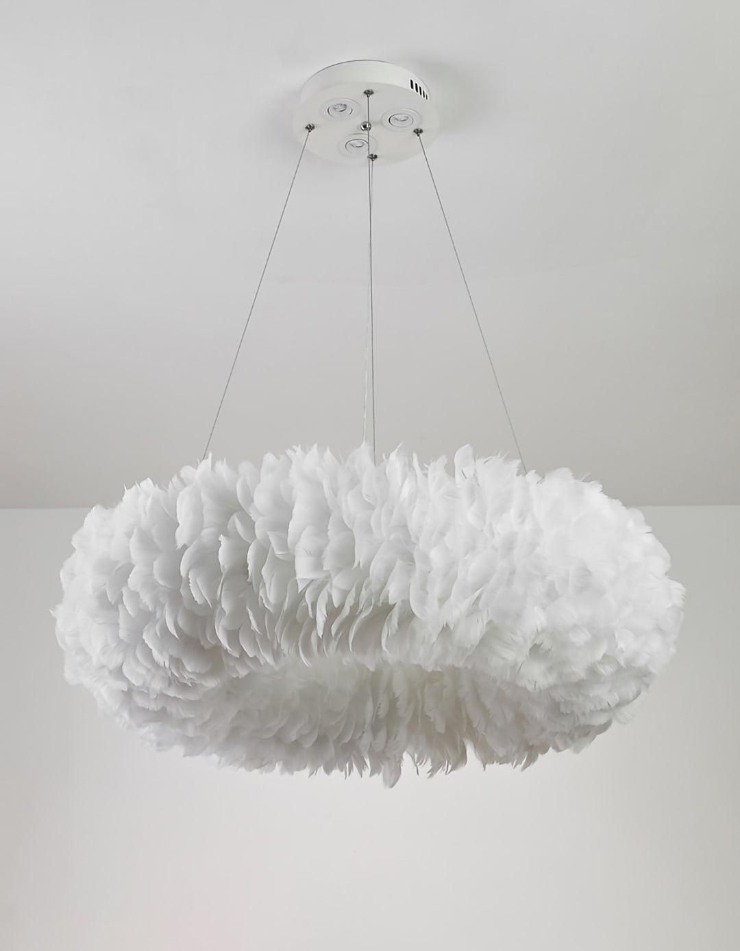 A Clérachic feather ring pendant unlit, showing the white feathers in layers, on three cables against a white wall.