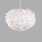 A round, fluffy Clérachic feather pendant, unlit, on a white cable against a flat grey background.