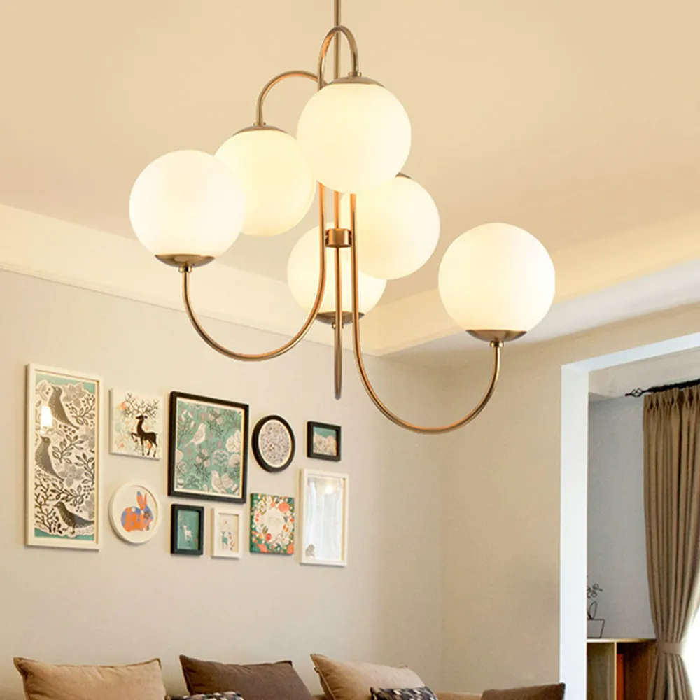 Clérachic gooseneck chandelier glowing above a living room gallery wall, with its gold arms and opal globes over a sofa.