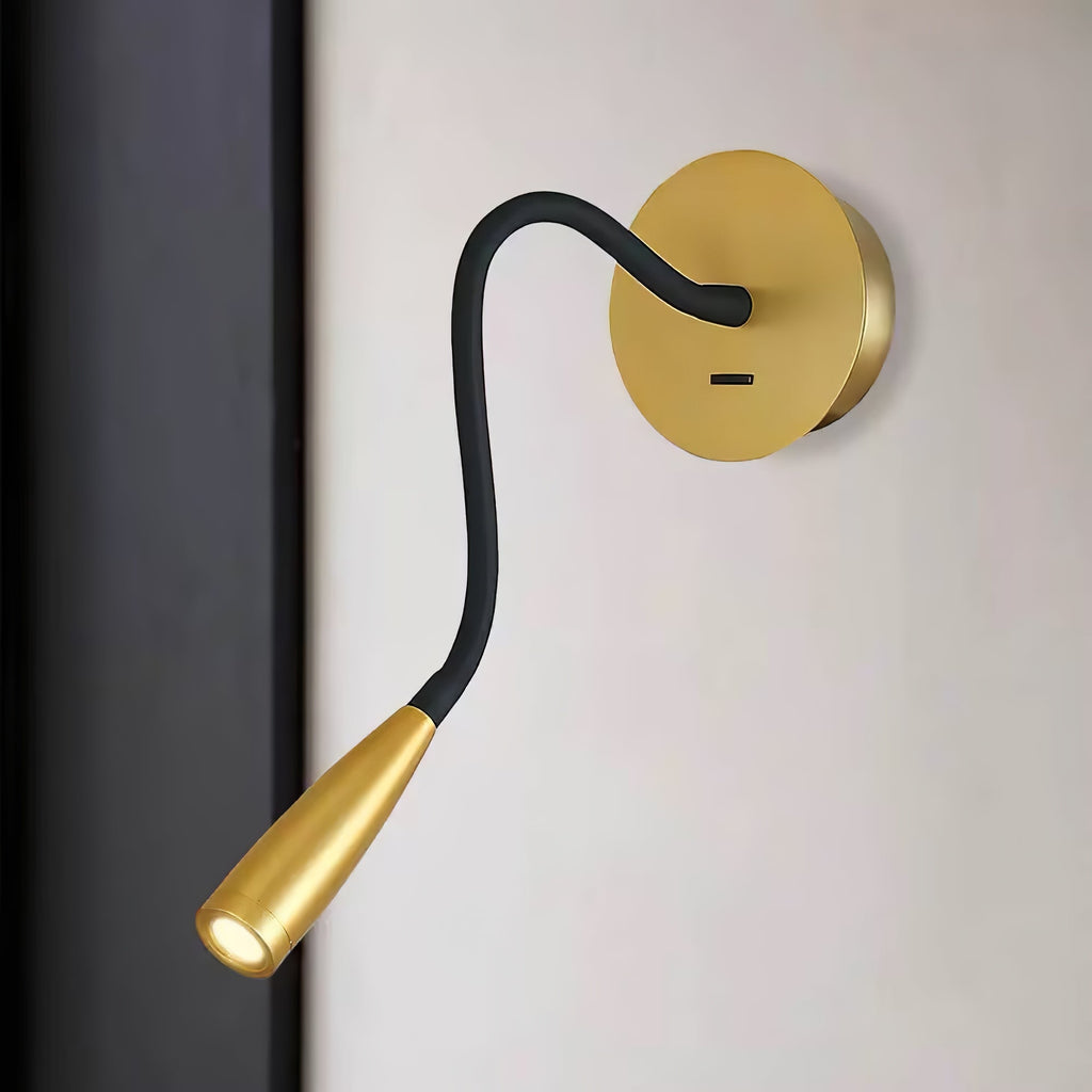 Close view of the round gold backplate, black curved arm and tapered gold spot head of this Clérachic wall light on a pale wall.