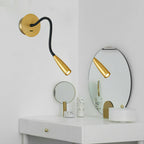 This Clérachic wall light hangs above a white dressing table with an oval mirror that reflects its gold spot head, plus a small round mirror.