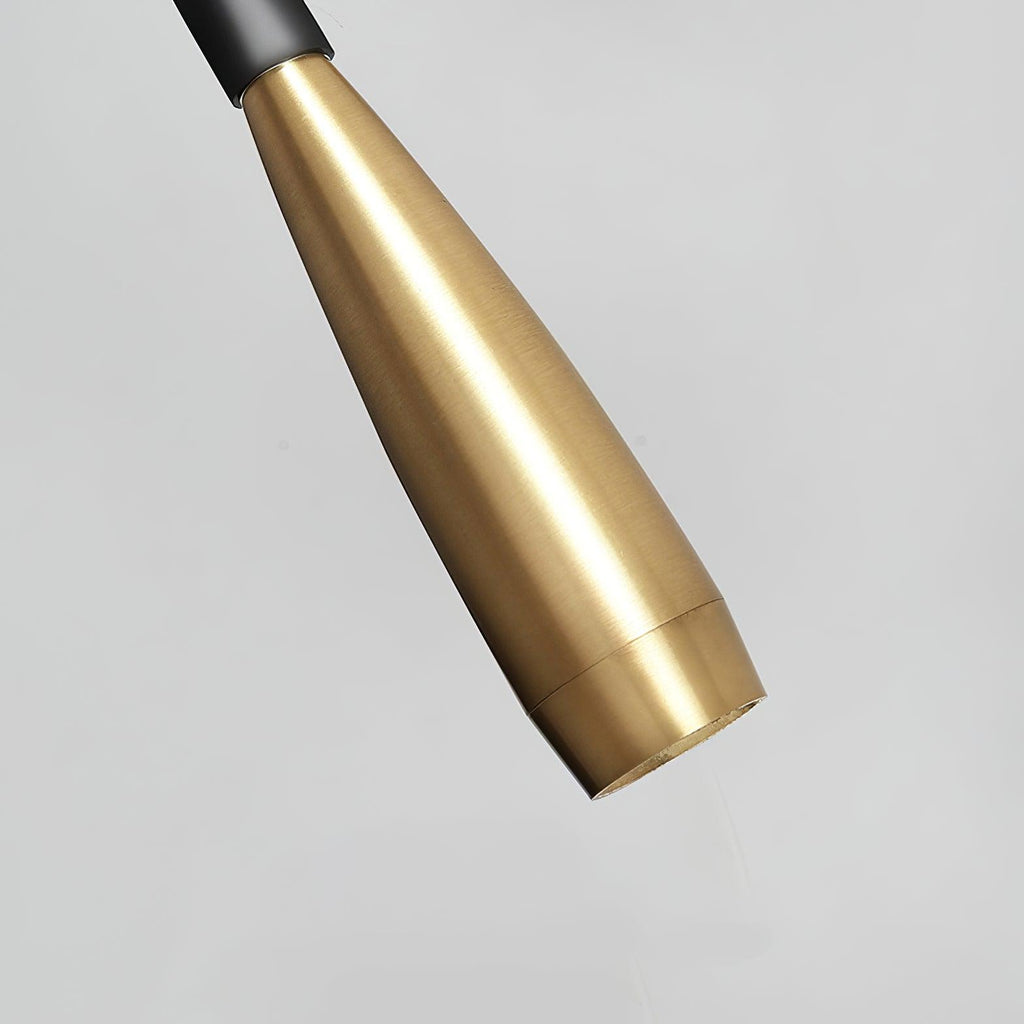 Close view of the tapered brushed gold spot head of this Clérachic wall light, ending in a small round lens on a pale grey ground.