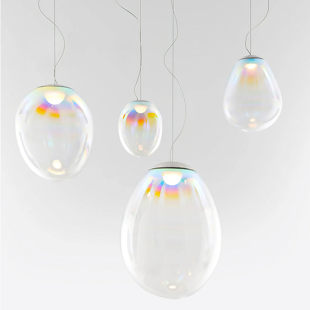 Four Clérachic glass teardrop pendants of different sizes hang at staggered heights against a pale grey wall, each with a coloured top.