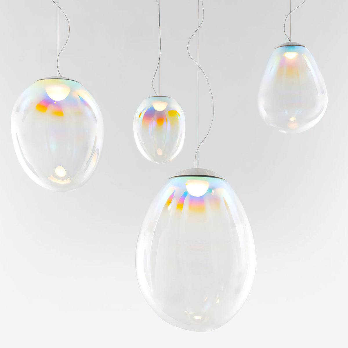 Four Clérachic glass teardrop pendants of varied size glow against a light backdrop, each with a rainbow sheen around its top cap.