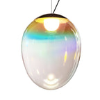 This Clérachic glass pendant lit on white, with a bright bulb under a dark cap and turquoise, gold and pink bands on the clear shade.