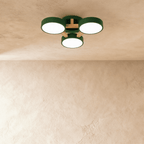 Clérachic's ceiling light in green, three drum shades on a light wood cross bar, photographed from below.