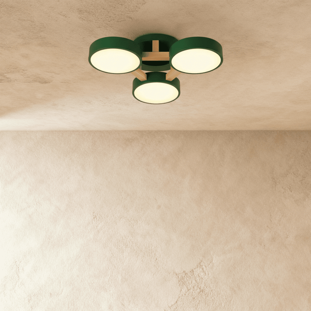 A closer view of the Clérachic ceiling light in green, its three drum diffusers lit warmly overhead.