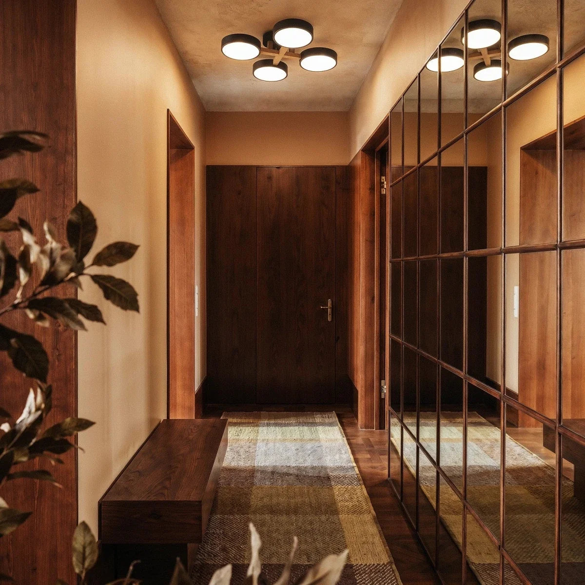The Clérachic ceiling light in gray, its four-head design glowing above a walnut-paneled hallway below.