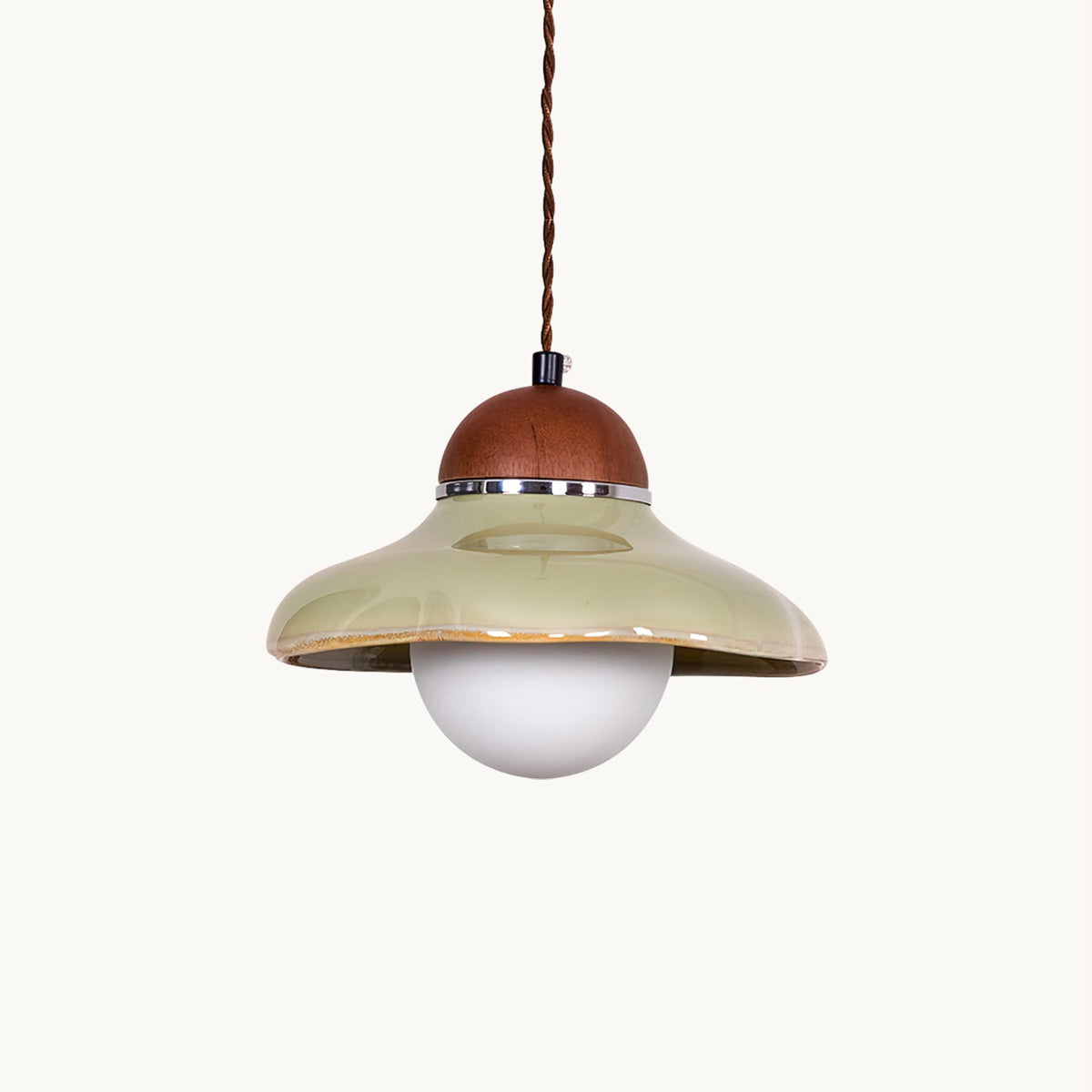 Green ceramic Clérachic dome pendant with a walnut-coloured wooden cap and a round frosted glass globe, on a white backdrop.