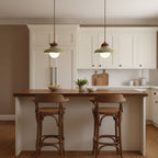 Pair of green ceramic Clérachic pendants over a kitchen island with a walnut top and two wooden stools.