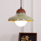 Underside view of this Clérachic green ceramic pendant, showing the glowing frosted globe and the yellow glaze inside the shade.