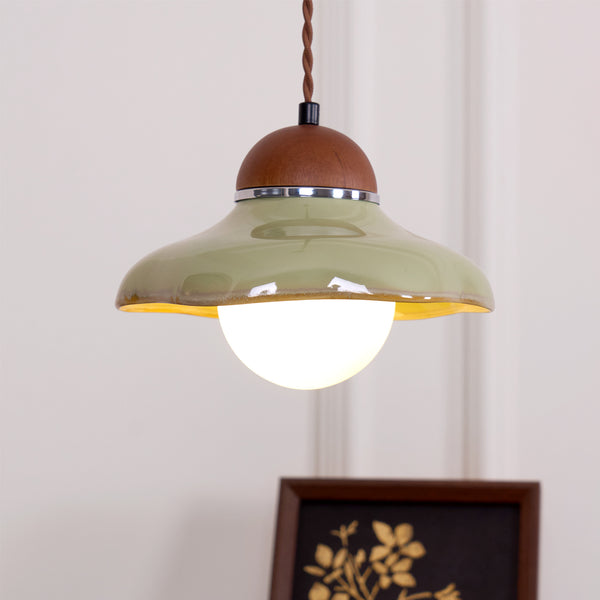 Underside view of this Clérachic green ceramic pendant, showing the glowing frosted globe and the yellow glaze inside the shade.