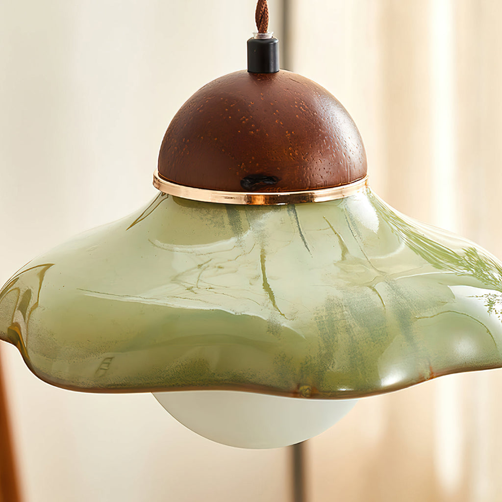 Close view of the green glaze streaks and the gold-toned ring beneath the walnut cap of this Clérachic pendant.