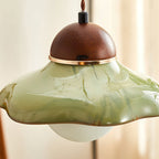 Close view of the green glaze streaks and the gold-toned ring beneath the walnut cap of this Clérachic pendant.
