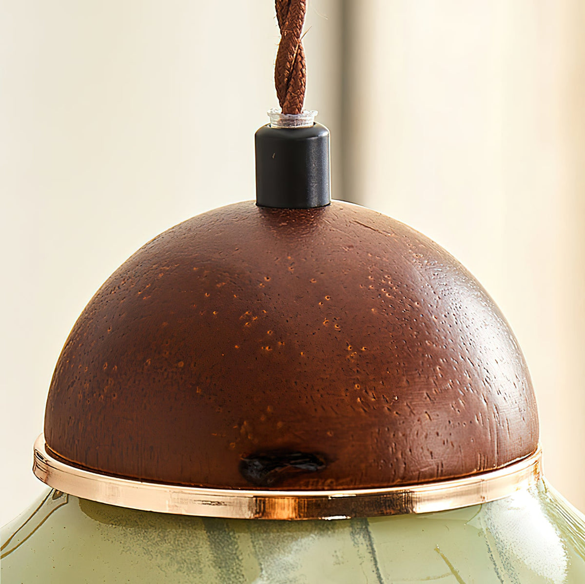Close view of the wooden dome cap, black cord grip and gold-toned ring on this Clérachic pendant.