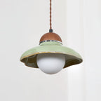 Clérachic green ceramic pendant with an unlit white globe, seen against a pale curtain.