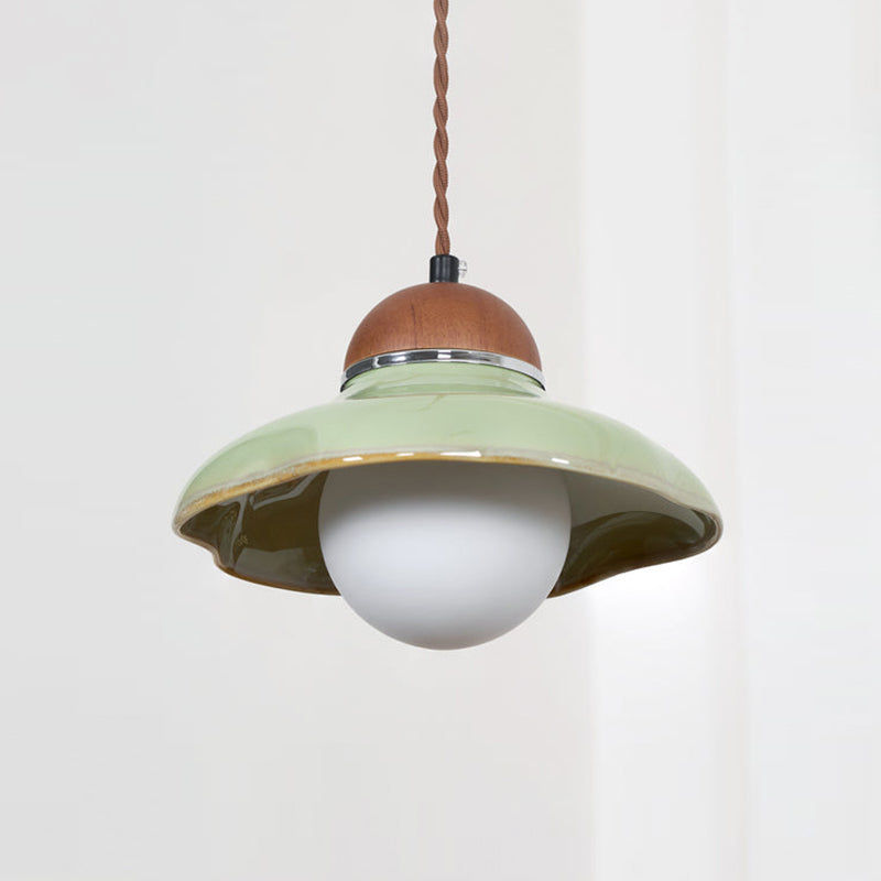 Clérachic green ceramic pendant with an unlit white globe, seen against a pale curtain.