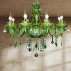 Clérachic green glass chandelier with eight curving candle arms and cascading green crystal drops, hung against a plaster wall.