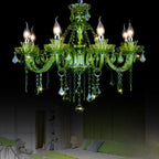 Clérachic eight-arm green glass chandelier lit above a softly lit bedroom with green cushions, set against a dark backdrop.