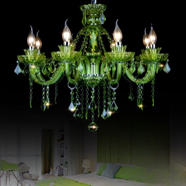 Clérachic eight-arm green glass chandelier lit above a softly lit bedroom with green cushions, set against a dark backdrop.