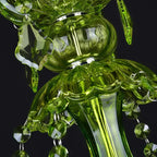 Close view of the green glass column and ribbed candle cup on a Clérachic chandelier, with faceted crystal drops hanging beside it.