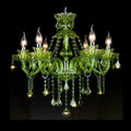 Clérachic six-arm green glass chandelier with candle bulbs and faceted crystal drops, lit against a black backdrop.