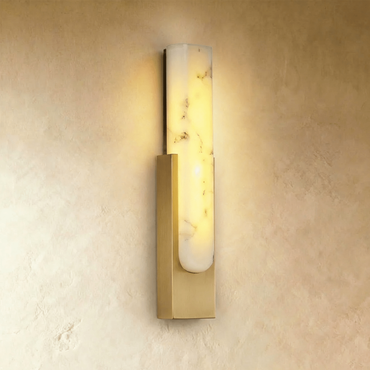 Clérachic gold-framed alabaster wall sconce, its veined stone panel glowing warmly against a plaster wall.