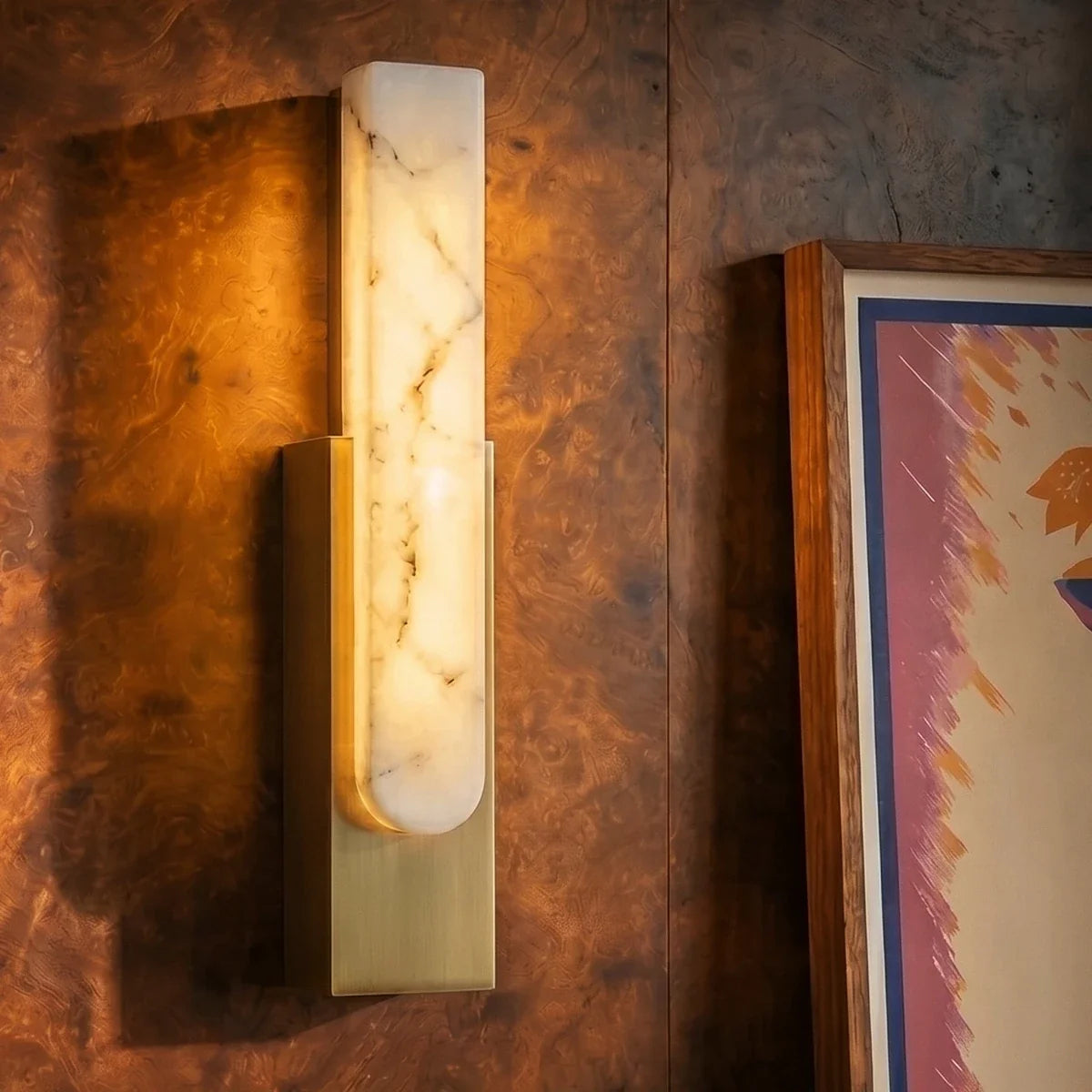 Close view of the Clérachic gold-framed alabaster sconce mounted on richly grained burl wood paneling.