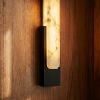 Close-up of the Clérachic black iron frame holding the alabaster sconce's veined stone panel on walnut paneling.